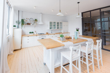 Stylish kitchen in light colors in a trendy modern duplex apartment with large high windows.
