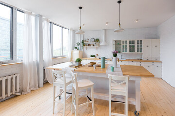 Stylish kitchen in light colors in a trendy modern duplex apartment with large high windows.