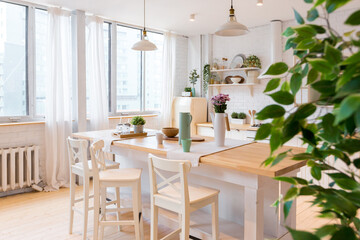Fototapeta na wymiar Stylish kitchen in light colors in a trendy modern duplex apartment with large high windows.