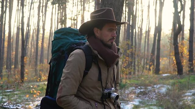 A man with a camera walks along a trail in the forest. Travel concept. Back light Slow motion