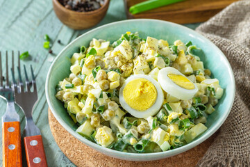 Spring salad with egg, green peas and green onions in a bowl on a rustic table.