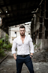 Fashion and stylish young male poses on broken building background. Handsome man in white shirt.