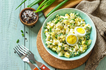 Spring salad with egg, green peas and green onions in a bowl on a rustic table. Copy space.