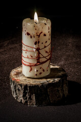 Gloomy bloody burning candle on a wooden stand - 404104665