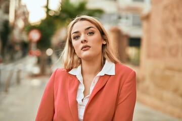 Fototapeta premium Young blonde businesswoman with serious expresison standing at the city.