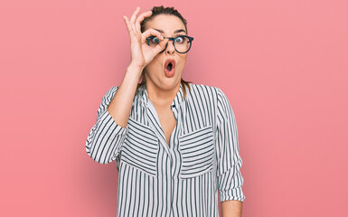 Young caucasian woman wearing business shirt and glasses doing ok gesture shocked with surprised...
