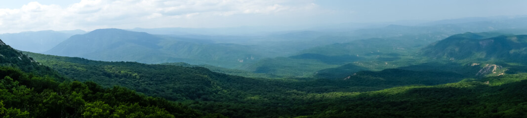 Obraz premium A view of the mountains covered with dense forest from the upper plateau of the Chatyr-Dag mountain range in Crimea. Panorama
