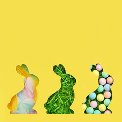 A silhouette of a rabbit is cut out of paper. Background of green grass. Happy Easter greeting card in trendy colors. Yellow and gray are the colors of 2021.