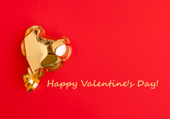 Fototapeta na wymiar Gold ball in the shape of a heart on a red background and text. Valentine's Day holiday concept. Postcard.
