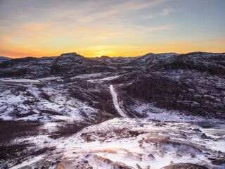 Icy winter road through the tundra hills in Teriberka. Amazing colorful Arctic landscape.