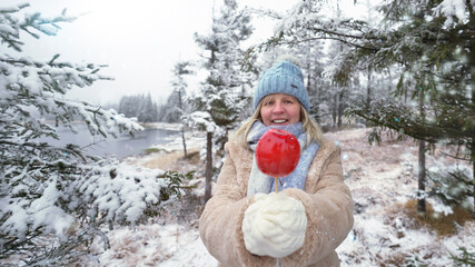 Frau im Winterwald mit roten Apfel
