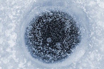 Air bubbles in ice, water hole in wintertime