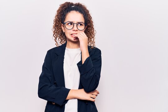 Beautiful kid girl with curly hair wearing business clothes and glasses looking stressed and nervous with hands on mouth biting nails. anxiety problem.