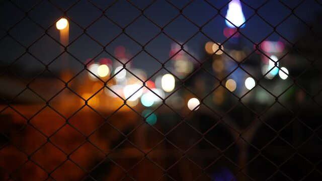 Bokehed City Lights and a Train Passing by over a Wire Fence
