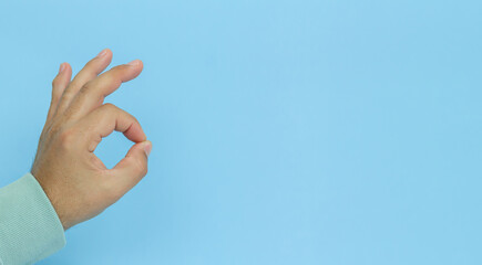 Male hand gesturing OK sign on blue background