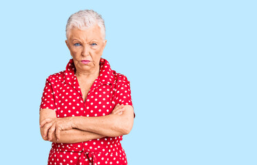 Senior beautiful woman with blue eyes and grey hair wearing a red summer dress skeptic and nervous,...