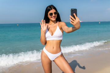 Young woman use her mobile phone to live broadcast video online with friends and say hello sharing...