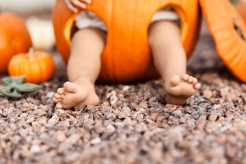Closeup of baby legs inside orange pumpkin at Halloween, season holiday concept
