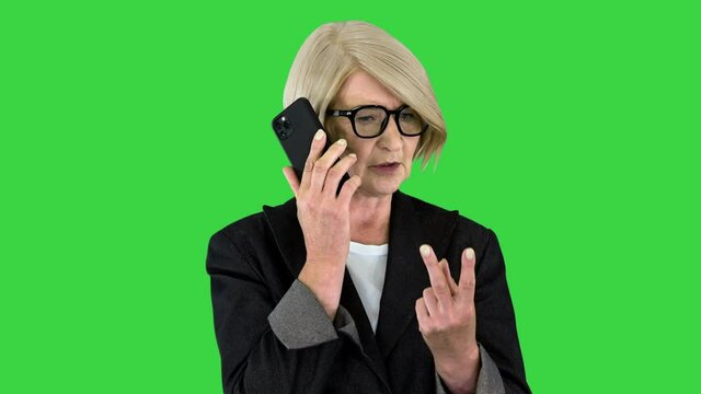 Aged serious senior woman talking on the phone on a Green Screen, Chroma Key.