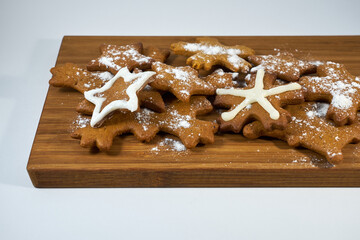 Ginger biscuits with sugar powder on a wooden board on a white background.