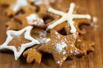 Ginger biscuits with sugar powder on a wooden board.