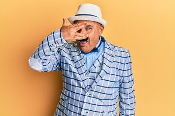 Mature middle east man with mustache wearing vintage and elegant fashion style peeking in shock covering face and eyes with hand, looking through fingers with embarrassed expression.