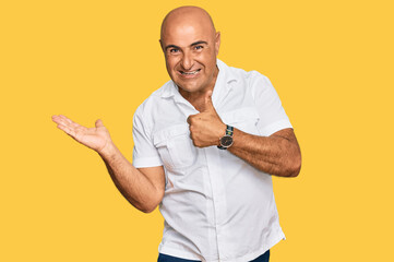 Mature middle east man with mustache wearing casual white shirt showing palm hand and doing ok gesture with thumbs up, smiling happy and cheerful