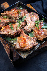 Traditionell gegrillte dry aged Kalbskotelett serviert als close-up in einem rustikalen Tablett auf schwarzen Board