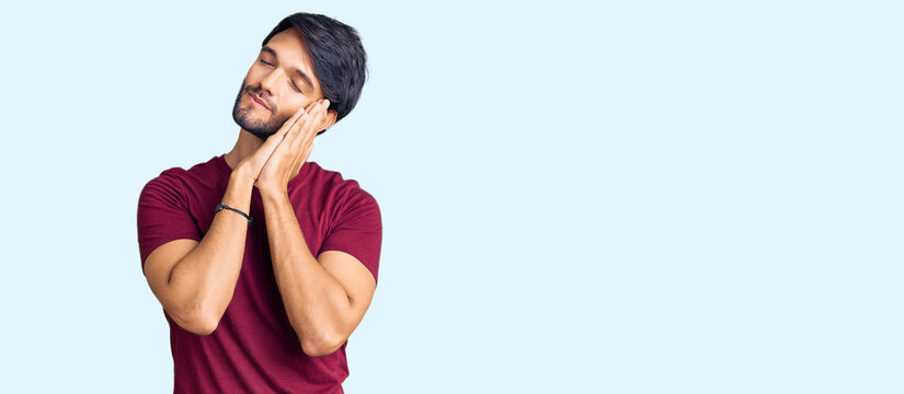 Handsome hispanic man wearing casual clothes sleeping tired dreaming and posing with hands together while smiling with closed eyes.