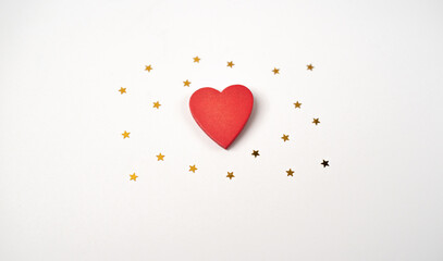 Red wooden heart and little golden stars on the light (white) background. Valentine's Day concept. Flat lay, top view.