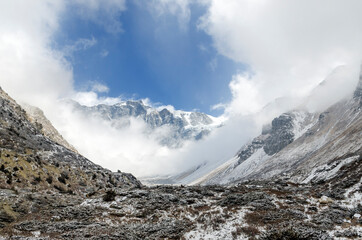 Fototapeta na wymiar Winter landscape with mountain peaks appearing behind clouds near Yak Kharka, Annapurna Circuit, Nepal