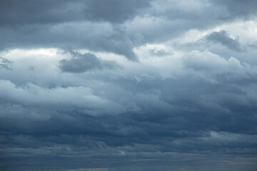 Fototapeta premium Natural color dramatic dark blue cloudy sky with wavy rippling clouds aligned above horizon, taken with wide angle 35 mm lens for sky replacement