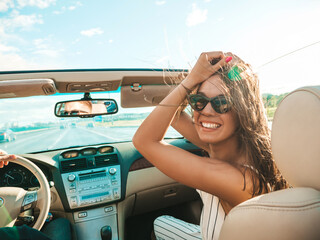 Portrait of young beautiful and smiling hipster female in convertible car. Sexy carefree woman...
