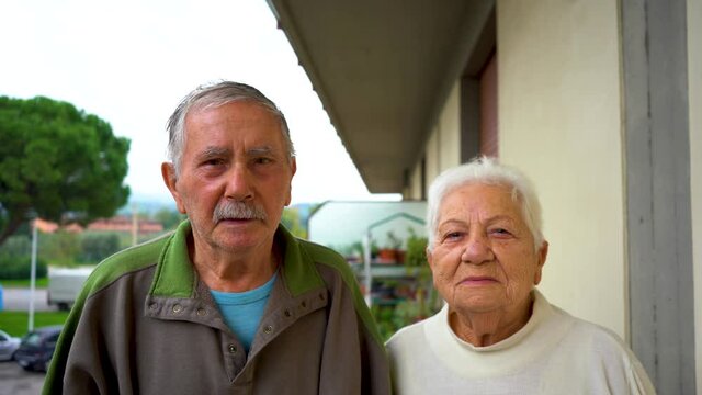an elderly caucasian married couple looks at the camera.