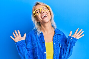 Young blonde girl wearing casual clothes and glasses celebrating mad and crazy for success with...