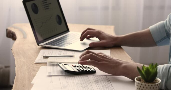 Man working use calculator and laptop, graphs stats on device screen close up. Accountant analyze company charges, calculate expenses, reporting research results, makes data entry, accounting concept