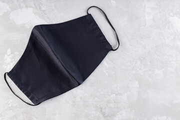 Naklejka premium Face protective mask on ultimate gray background. Antivirus mask made from black cotton. Black face homemade mask to protect against flu and virus. Copy space. Top view