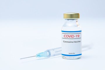 Bottle of coronavirus vaccine with syringe background.