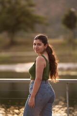 Naklejka premium A beautiful young woman poses for the camera from the back in a mid-length shot in a city center park