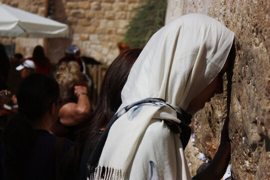Eine junge Frau mit Kopftuch steht an der Klagemauer in Jerusalem und betet.