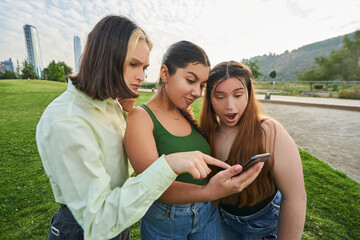 group of teenage friends check the cell phone of one of their friends pointing out an important issue that they should pay attention to