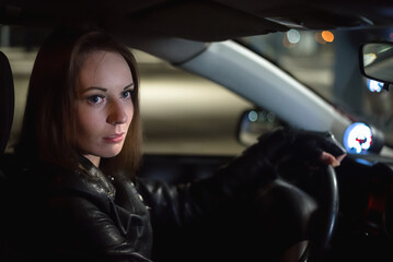 Obraz na płótnie Canvas Young girl a driver by the car steering wheel.