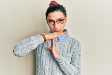 Young caucasian woman wearing casual clothes and glasses doing time out gesture with hands,...