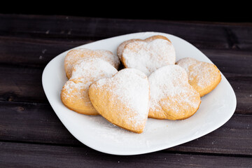 cookies for the Valentine's Day holiday, Heart-shaped cookies on a black background, on a white plate.