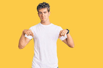 Fototapeta premium Young handsome man wearing casual white tshirt pointing down looking sad and upset, indicating direction with fingers, unhappy and depressed.