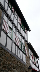 Haus in Fachwerk Stil mit kleinen Butzenfenstern und rot und weiß gestreiften Fensterläden in der Altstadt von Kronberg im Taunus