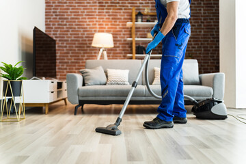 Man In Uniform Vacuuming House Floor