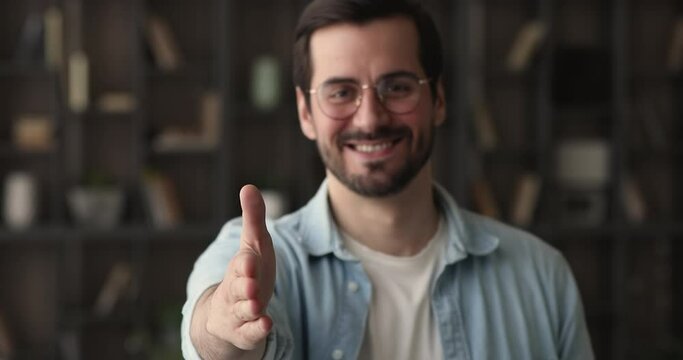 Confident businessman in glasses standing in office room smile reaching out his arm for handshake, closeup view. HR manager employer welcomes in company new worker, greeting, first impression concept