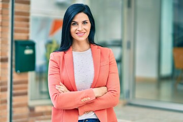 Young beautiful businesswoman with crossed arms smiling happy standing at the city.