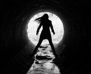 silhouette of a young woman in the coc of the tunnel. A sewer tu